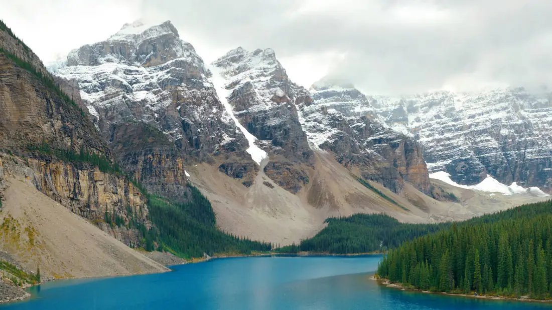 Turquoise Moraine Lake below snow-capped peaks and pine forest in Banff National Park, Canada